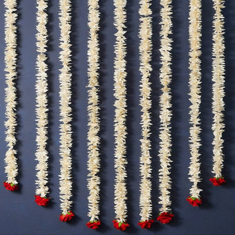 Decorative string with white floral strands and red flower buds on a dark blue background