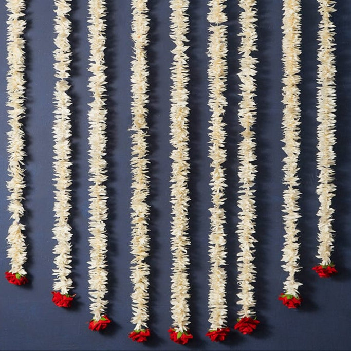 Decorative string with white floral strands and red flower buds on a dark blue background